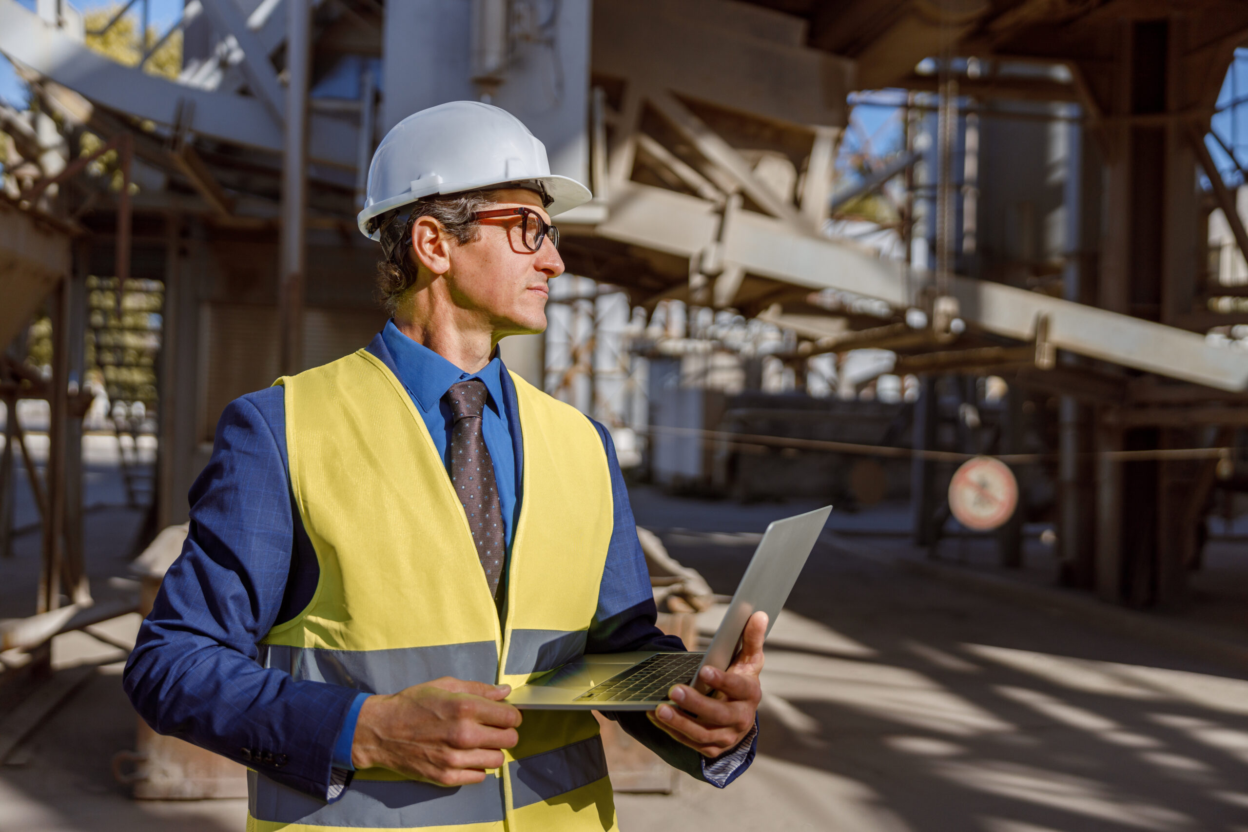 Male Worker With Laptop Standing Outdoors At Factory - Quero montar uma empresa